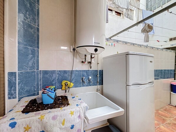 A bathroom with a bathtub, a sink, and a toilet. There is a showerhead mounted on the wall, and a towel rack above the sink.