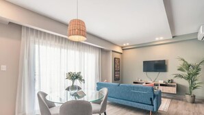 Un salon moderne avec un canapé bleu, une table en verre et un luminaire suspendu.