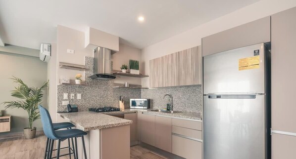 Eine moderne Küche mit Edelstahl-Kühlschrank, Granit-Arbeitsplatten und integriertem Mikrowellenherd.