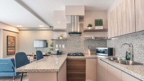 Une cuisine moderne dotée de plans de travail en granit, d’appareils électroménagers en acier inoxydable et d’armoires en bois.