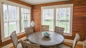 A dining area with a round table, four wicker chairs, and a bowl on the table. - Homeplace 1936 | Walk to Downtown West Jefferson | Historic High Country Stay (West Jefferson)