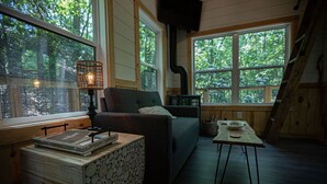A cozy cabin interior with a sofa, a table with a lamp, and a fireplace.