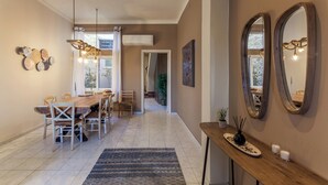 Un comedor moderno con una mesa y sillas de madera, un tapete estampado y una consola con velas y un jarrón.