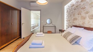 Un dormitorio con una cama grande, un armario, una mesita de noche, un espejo y vistas al balcón exterior.