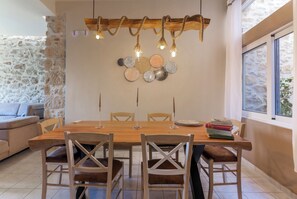 A dining area with a wooden table, six chairs, and a decorative wall hanging above.