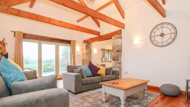 A spacious living room with wooden beams, a stone wall, and a large window. - Coastal Barn Conversion, overlooking the stunning Cot valley. (Saint Just)