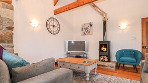 A cozy living room with a fireplace, a television, and comfortable seating. - Coastal Barn Conversion, overlooking the stunning Cot valley. (Saint Just)