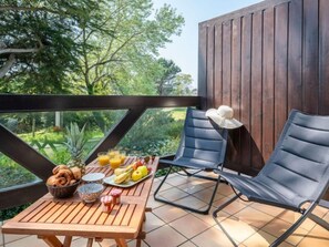 Une table en bois, dressée pour le petit-déjeuner, avec deux chaises et une vue sur la verdure.