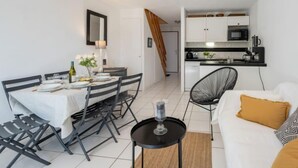 Un espace de vie compact comprenant un coin repas, une kitchenette et un coin salon.