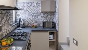 A compact kitchen with a gas stove, microwave, and a small countertop. - Daydreaming by Interhome (Meta di Sorrento)