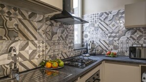 A modern kitchen with patterned tiles, stainless steel appliances, and a built-in oven. - Daydreaming by Interhome (Meta di Sorrento)