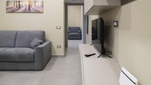 A modern living room with a grey sofa, a flat-screen TV, and a white radiator. - Daydreaming by Interhome (Meta di Sorrento)