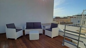 A rooftop deck with white furniture, including sofas and a small table, under a clear sky. - Daydreaming by Interhome (Meta di Sorrento)