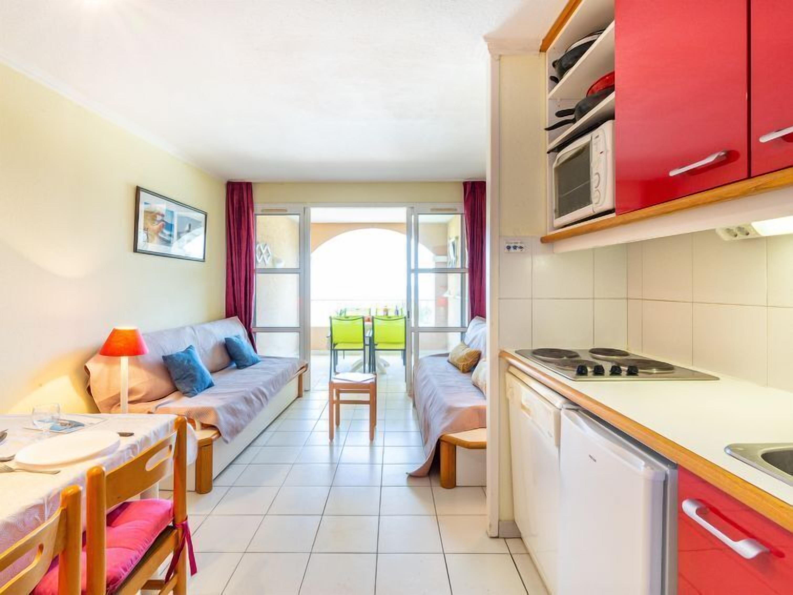 Habitació compacte amb una cuineta, zona de dinar i un sofà.