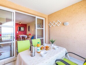 A dining area with a table set for two, a coffee pot, and a bottle of orange juice.