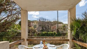 An outdoor patio with a table set for two, overlooking a rocky landscape. - Super Plage by Interhome (Saint Cyr sur mer Les Lecques)