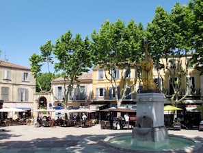A public square with outdoor seating, a fountain, and buildings with shops and cafes.