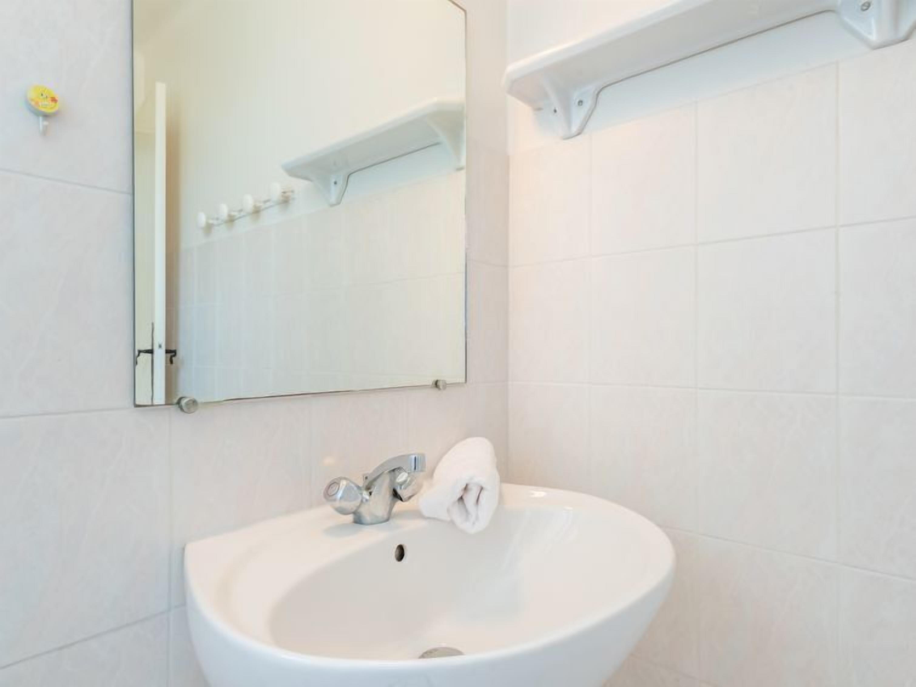 A bathroom with a white sink, a mirror, and a towel hanging on the wall.