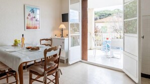Un coin repas avec une table dressée pour deux personnes, une chaise, une lampe et un tableau accroché au mur.