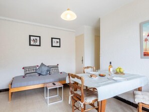 Una habitación acogedora con una cama, una mesa de comedor con sillas y un taburete pequeño. Hay cuadros enmarcados en la pared y un cuadro sobre la mesa.