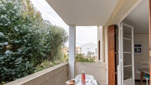 Ein Balkon mit Tisch für zwei Personen, einer Flasche und Gebäck.