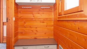 Ein kleiner, abgeschlossener Raum mit Holzwänden und einem weißen Schrank über einer braunen Arbeitsplatte.