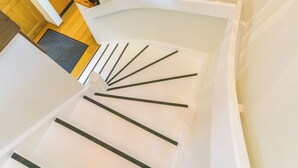 Un escalier en colimaçon avec des marches blanches et des rampes noires.