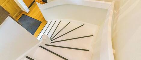 A spiral staircase with white steps and black handrails.