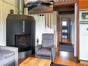 Ein Wohnzimmer mit Kamin, einer Couch, einem Holztisch und Meerblick durch ein Fenster.