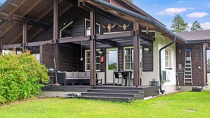 Une cabane en bois dotée d’une véranda, d’un espace extérieur aménagé pour s’asseoir et d’une zone couverte.