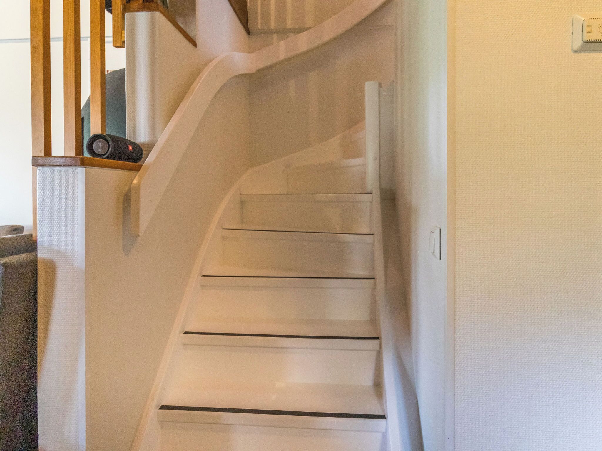 A white spiral staircase with wooden handrails and a handrail on the right side.