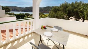 A balcony with a table set for two, overlooking a scenic landscape with trees and hills. - Edifici Port del Rei by Interhome (L'Escala)