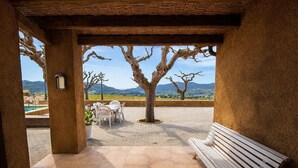 Une terrasse extérieure avec une table et des chaises, un banc et une vue sur le paysage.