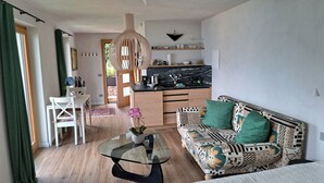 A modern living room with a glass coffee table, patterned sofa, and a dining area with a white chair. - Casa Lago Azzurro Atelier relaxation puur for vacation & time out (Cannobio)