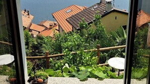 A room with a large window overlooking a body of water and distant mountains. - Casa Lago Azzurro Atelier relaxation puur for vacation & time out (Cannobio)