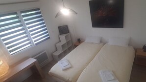 A bedroom with a bed, bedside tables, a desk, a lamp, a window with blinds, a wall-mounted artwork, and a staircase. - Condette, ideally located house! (Condette)