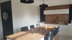 A modern dining area with a wooden table and chairs, a black pendant light, and a kitchen in the background. - Condette, ideally located house! (Condette)