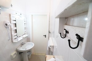 A bathroom with a sink, mirror, towel rack, and a hairdryer.