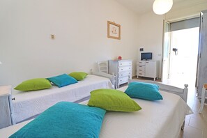 A hotel room with two beds, a desk with a computer, a chair, and a window with a view.