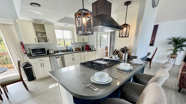 A modern kitchen with a central island, white cabinetry, and pendant lighting. - Beautiful relaxing home 4BR/3BA near Light Rail (Seattle)