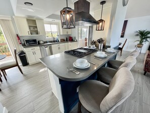 Een moderne keuken met een centraal eiland, witte kastjes en hanglampen.