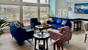 A spacious living room with a blue sofa set, a patterned armchair, and a round coffee table. - Beautiful relaxing home 4BR/3BA near Light Rail (Seattle)
