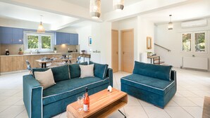 A modern living space with two sofas, a wooden coffee table, and pendant lighting. - Villa Olga by Corfuescapes (Corfu)