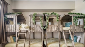 A room with four bunk beds, each with a wooden frame and a ladder. The beds are adorned with green foliage. - Heritage Crossing Magic | 3BR, 2 Bath Cozy Condo w/ Golf Course Views and Themed Room Near Disney (Kissimmee)