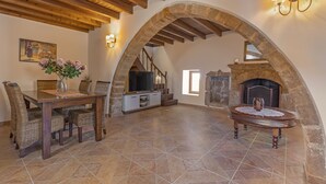 A spacious living area with a stone fireplace, wooden ceiling beams, and a dining table with wicker chairs. - ★ Bonseye 2Floor, sea, nature & relax ★ (Rhodes)