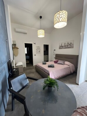 A modern bedroom with a bed, bedside tables, a desk, a chair, a round table with a plant, and two pendant lights. - Holiday Home "La Dimora della Luna" with Sea View, Terrace and Wi-Fi (Pozzallo)