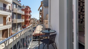 A balcony with a table and chairs, overlooking a street with buildings.