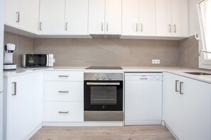 Una cucina moderna con mobili bianchi, forno, microonde e lavastoviglie.