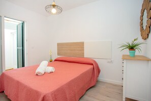 Una camera da letto con un letto, una lampada a parete, una pianta in vaso e una testiera in legno.