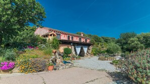 A rustic building with a tiled roof, surrounded by a garden with various plants and flowers. - Villa "Stazzu La Piredda" with Garden & Wi-Fi (Arzachena)